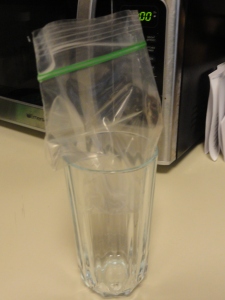 Placing the Ziploc bag into the glass